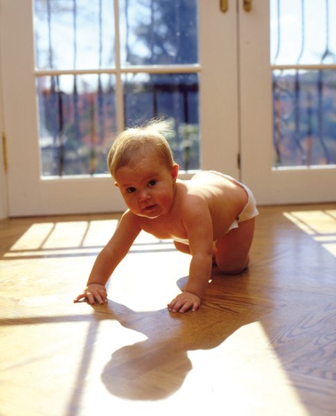Baby crawling on the floor in front of balcony glass doors
