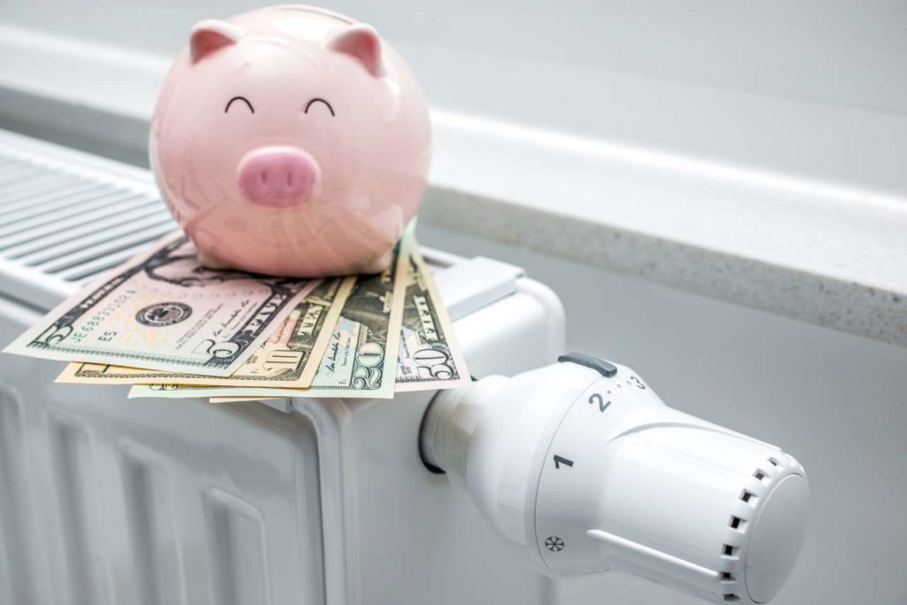 Image of a piggy bank sitting on bills on top of a cooling unit
